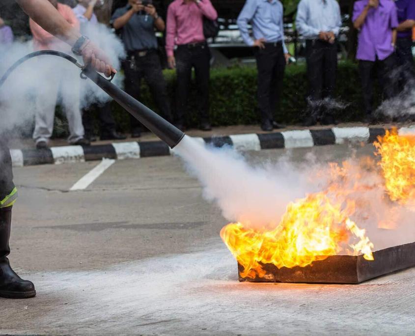 Instructor showing how to use a fire extinguisher on a training fire