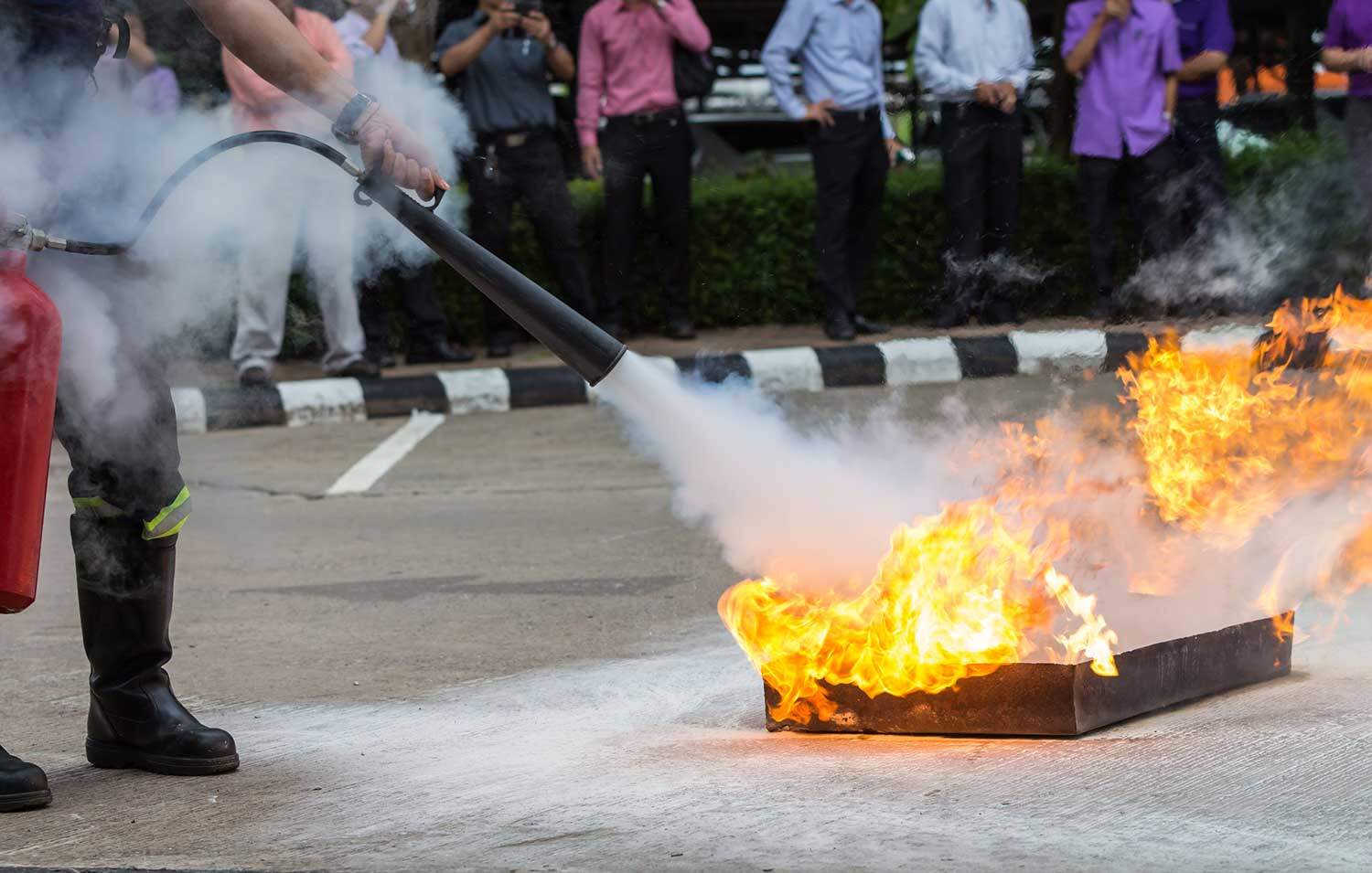 Instructor showing how to use a fire extinguisher on a training fire